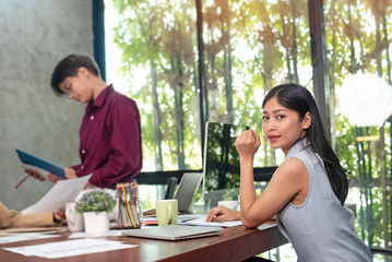 Young businesswoman working hard ,with colleagues team meeting,at office,plenty onf paper chart on wooden desk