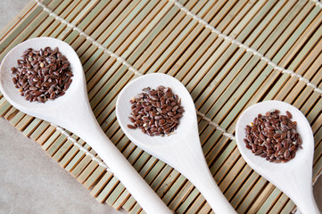 Flax seeds on three wooden spoons on the table, top view