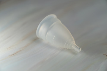 Menstrual cup on a white marble  background.