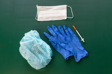 dark background. On it lie medical gloves, a syringe, a cap, and a bandage on his face. Close-up....