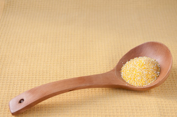 Wooden spoon with corn grits on the table