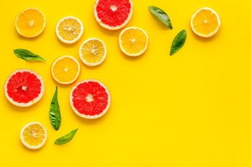 Citrus slices frame - lemons, grapefruits, leaves - on yellow background top-down copy space