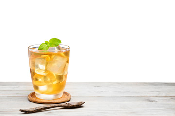 Tea or yellow herbal in a glass with ice And Peppermint added a fragrance on the wooden table Isolated on white background