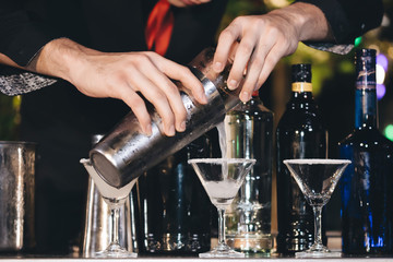 Close up of a delicious cocktail bartender putting slice of orange on. Bartender is making cocktail at bar counter