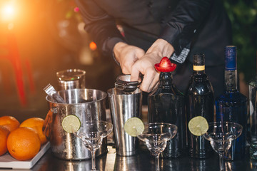 Close up of a delicious cocktail bartender putting slice of orange on. Bartender is making cocktail at bar counter