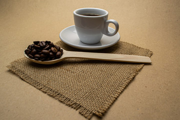 Cup of coffee on a napkin with a wooden spoon of coffee bean 