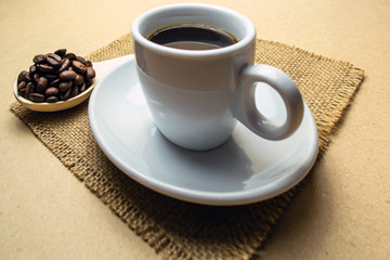 Cup of coffee on a napkin with a wooden spoon of coffee bean
