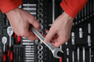 technician mechanic wearing red clothes holding chrome socket wrench tool on toolbox background for repair maintenance service