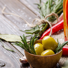 Closeup view of green olives oils and spices on kitchen table. Cooking concept