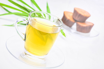Herbal ginger tea in clear glass On a white background with a cake backdrop Tables for drinks, healthy ideas.soft focus.