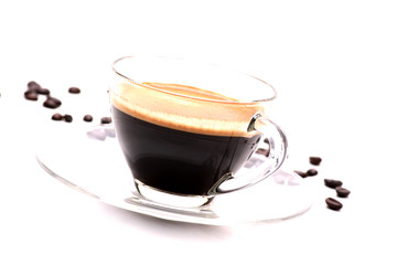 Black coffee in a clear glass on a white background with coffee beans in the background.soft focus.