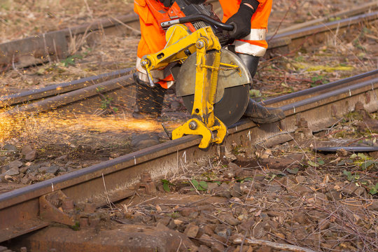 ein Arbeiter der Bahn zerschneidet mit einem Trennschleifer  Bahnschienen