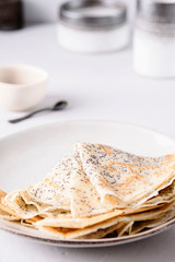 Crepes with poppy seed on grey background. Pancake week, mardi gras, maslenitsa holidays. Selective focus