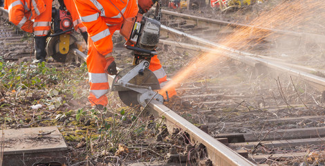 ein Arbeiter der Bahn zerschneidet mit einem Trennschleifer  Bahnschienen