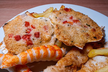 Grilled shrimp skewers. Scallops shell and surimi stick with fries. Wooden table. Close-up