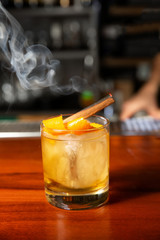 Orange cocktail with ice cube and orange zest.