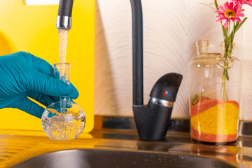 water purification specialist tap water pours into a glass flask.