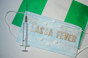 Nigerian flag under words Lassa fever outbreak concept. protective breathing mask and syringe....