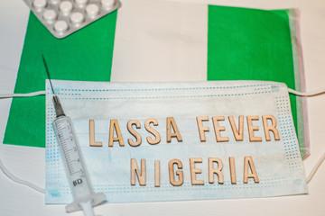 Nigerian flag under words Lassa fever outbreak concept. protective breathing mask and syringe....