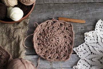 Fototapeta na wymiar Crochet process from soft woolen yarn of brown color. Woolen yarn on a wooden background.