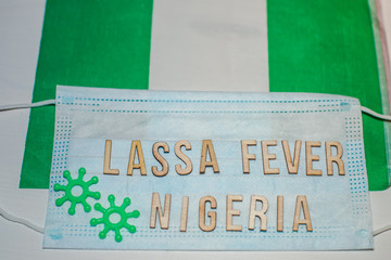 Nigerian flag under words Lassa fever outbreak concept. protective breathing mask and syringe....