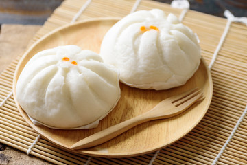 Steamed buns filled with minced pork and salted egg on wooden plate and fork, Chinese food
