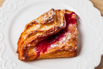 Puff pastry with red jam on a white plate