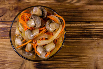 Canned mushrooms with carrot and onion in a ceramic bowl. Top view