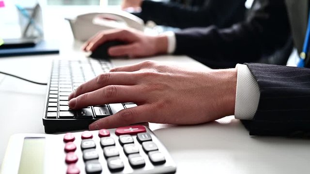 計算機とキーボードを扱う手元アップ