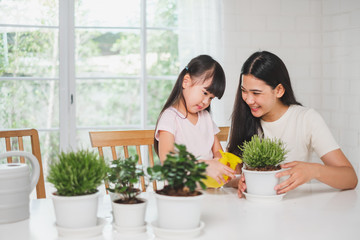 Asian cute girl help mother to plant flowers, watering at home, Asian family home gardening concept