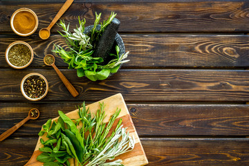 Making spices. Herbs in motar and dry flavorings on dark wooden desk top-down copy space