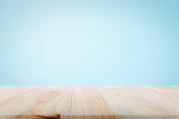Empty wooden deck table over light blue wallpaper background for present product.