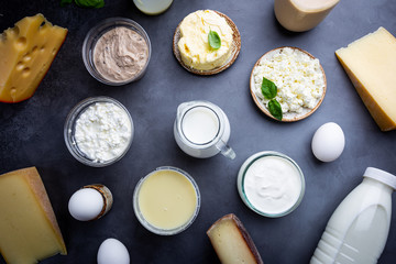 Fresh dairy products, milk, cottage cheese, eggs, yogurt, sour cream and butter on black background, top view