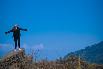 A young woman standing on a rock on a cliff