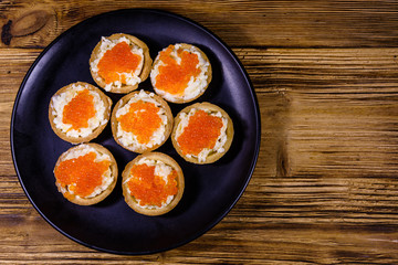 Tartlets with red caviar on a black plate. Festive food. Top view