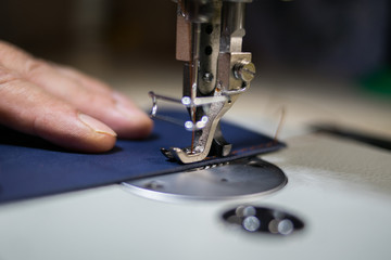 A man sews from leather on a sewing machine. Hands and sewing. Production of leather goods using a sewing machine
