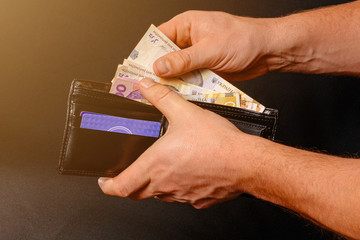 Ukrainian hryvnia in a black purse, a man holds in his hands.