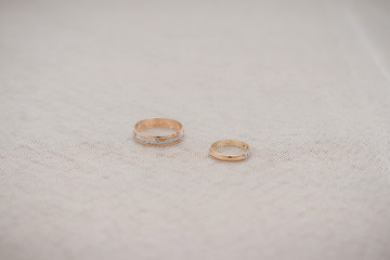 Wedding engagement rings in white and yellow gold on a light tulle background