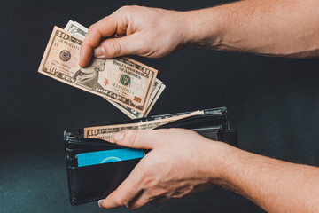 Leather wallet with money in male hands on dark background