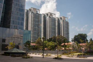 Fototapeta premium Tall houses stand behind a small area with trees