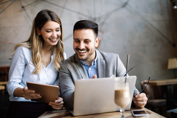 Business colleagues laughing and working while looking at the laptop
