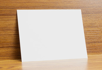 Blank a6 paper frame locked on wooden textured desk as template for graphic designers presentations, portfolios etc.