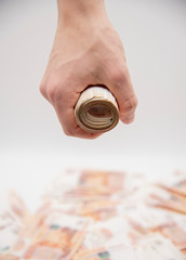 A man's hand is clenched into a fist holding twisted five-thousand-ruble bills