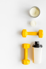 Sport nutrition. Whey protein, shaker, dumbbells on white background top-down flay lay copy space