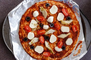 homemade vegetables pizza with olives and cherry tomatoes topping being prepared