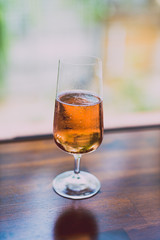 glass of chilled rose wine on wooden table next to window light with backyard bokeh