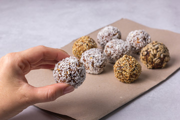 The woman's hand takes from the table a homemade energy ball of dried fruits and nuts.