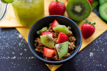 gesundes Frühstück: knuspriges Müsli mit frischen Erdbeeren und Kiwis in Nahaufnahme. Ansicht von oben