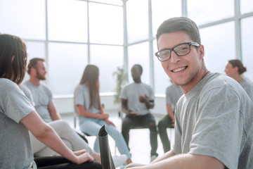 smiling young man sitting in a circle of like-minded people