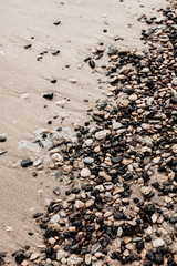 Different texture on the beach - water and sand, stones and pebbles, waves and splashes.